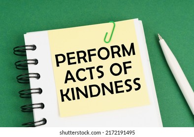 Business concept. On a green surface, a pen, a notepad with stickers and the inscription - Perform Acts of Kindness - Powered by Shutterstock