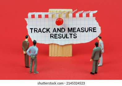 Business Concept. On A Red Background Are Miniature Figures Of People Looking At An Ad With The Inscription - Track And Measure Results