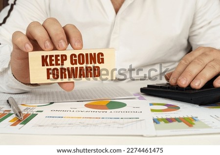 Business concept. On the table are business charts and diagrams in the hands of a wooden block with the inscription - Keep Going Forward