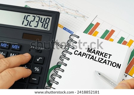 Business concept. On the table there is a calculator, reports with graphs and a notepad with the inscription - Market capitalization