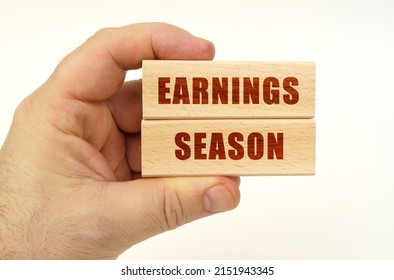 Business Concept. On A White Background, A Hand That Holds Wooden Blocks With The Inscription - Earnings Season