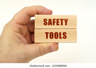 Business Concept. On A White Background, A Hand That Holds Wooden Blocks With The Inscription - Safety Tools