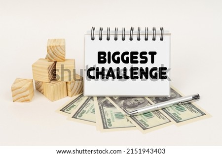Business concept. On a white surface, cubes, dollars, a pen and a notepad with the inscription - Biggest Challenge