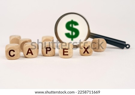 Business concept. On a white surface, a magnifying glass with a dollar symbol and cubes with the inscription - CAPEX