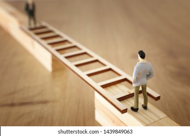 business concept picture of challenge. A man stands on the edge of a high wall and passes the gap by placing a ladder. Problem solving and decisionmaking.