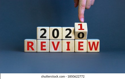 Business concept of planning 2021. Male hand flips a wooden cube and changes the inscription 'Review 2020' to 'Review 2021'. Beautiful grey background, copy space.