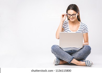 Business concept. Portrait of happy woman in casual sitting on floor in lotus pose and holding laptop isolated over white background. 