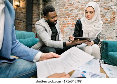 Business concept of signing the joint contract. Beautiful muslim business lady in white hijab sitting together with her bearded african business partner and signing the contract in the office room - Powered by Shutterstock