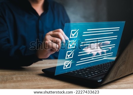 Business concept and smart checklist on virtual screen,A man use a pen marking about exploring the topics on the digital form check sheet and use a laptop working in a modern office