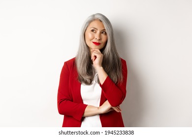 Business Concept. Smiling Mature Lady In Red Blazer, Smiling And Looking Satisfied While Thinking, Standing Over White Background