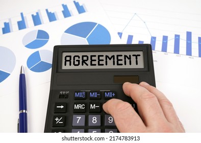 Business Concept. There Is A Calculator On Documents With Graphs And Diagrams. On The Scoreboard Of The Calculator Is The Inscription - Agreement