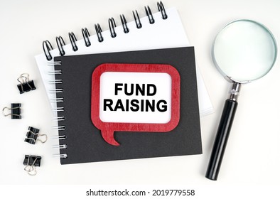 Business Concept. There Is A Magnifying Glass, A Notebook And A Sign On The Table - FUND RAISING