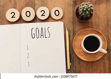 Business concept of top view 2020 goals list with notebook, cup of coffee over wooden desk - Shutterstock ID 1538973677