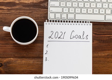 Business Concept Of Top View 2021 Goals List With Notebook, Cup Of Coffee Over Wooden Desk.