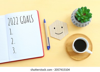 Business concept of top view 2022 goals list with notebook, cup of coffee over wooden desk
