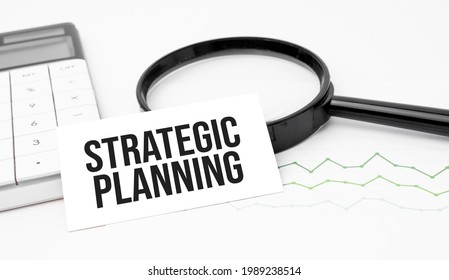 Business Concept. Top View Of Calculator, Magnifier, Pen, Table Clock And Notebook Written Strategic Planning On Wooden Background.