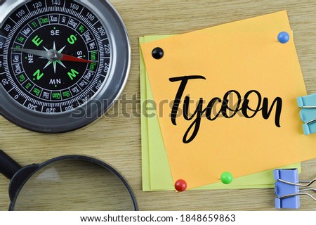 Business concept. Top view of compass, magnifying glass and memo notes written with text Tycoon. Selective focus.