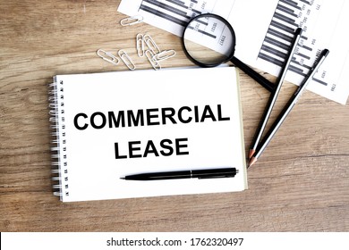 Business concept. Top view of desktop with diagram, magnifying glass. The word commercial lease is written on a notebook.