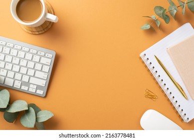 Business concept. Top view photo of workspace white keyboard planners computer mouse stationery gold pen clips cup of coffee on wooden stand and eucalyptus on isolated orange background with copyspace