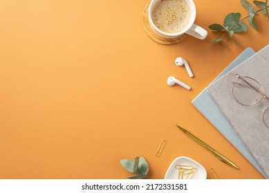 Business concept. Top view photo of workspace cup of coffee on wooden stand wireless earbuds glasses diaries gold pen clips eucalyptus on isolated orange background with copyspace - Powered by Shutterstock