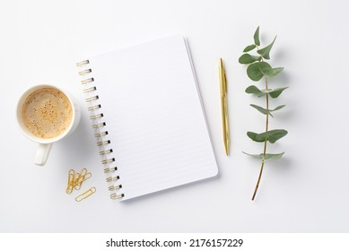 Business concept. Top view photo of workplace open notepad cup of coffee clips gold pen and eucalyptus sprig on isolated white background with blank space