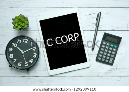 Business concept. Top view of plant,clock,calculator,pen and tablet written with C Corp on white wooden background,