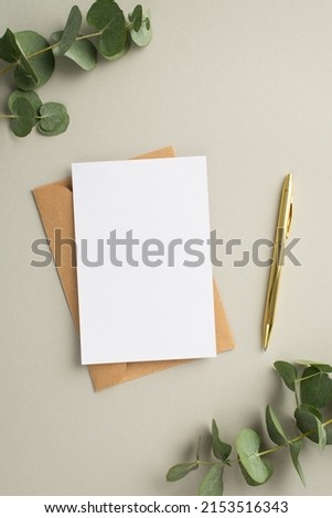 Business concept. Top view vertical photo of paper card craft paper envelope gold pen and eucalyptus on pastel grey background with blank space