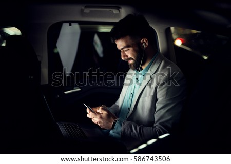 Business concept. Typing message on smart phone in the car. Working late.