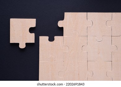 Business concept with wooden jigsaw puzzle on black background. Incomplete wooden puzzles, top view, flat lay. The concept of logical thinking, conundrum.