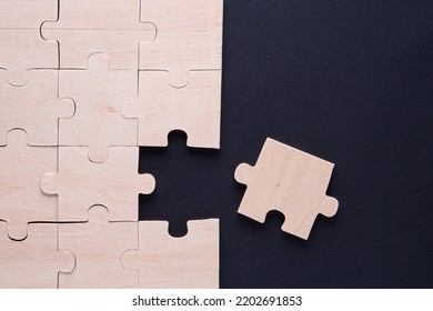 Business concept with wooden jigsaw puzzle on black background. Incomplete wooden puzzles, top view, flat lay. The concept of logical thinking, conundrum.