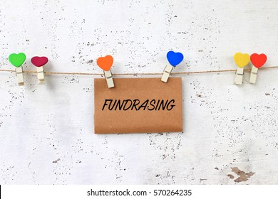 Business Concept - Words On Paper Writing FUNDRAISING With Wooden Clamps On Rustic Wooden Background.