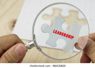 Business concept.Hand with magnifying glass searching for a piece of jigsaw puzzle with LEADERSHIP word. - Shutterstock ID 386520820