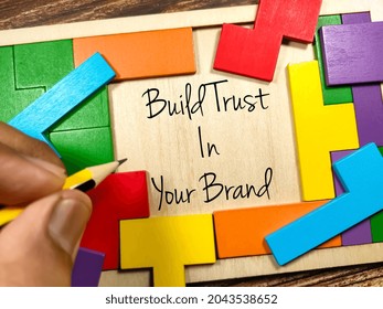 Business Concept.Text Build Trust In Your Brand Writing On Wooden Puzzle Board On A Wooden Background.