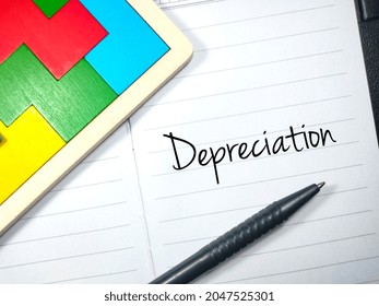 Business concept.Text Depreciation writing on notebook with pen and woooden puzzle