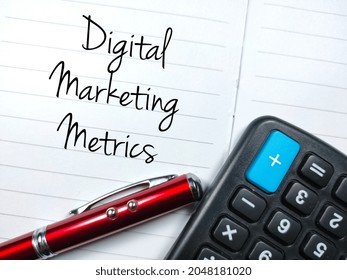 Business Concept.Text Digital Marketing Metrics Writing On Notebook With Pen And Calculator.Shot Were Noise And Film Grain.