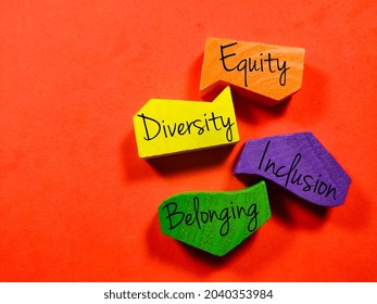 Business Concept.Text Equity Diversity Inclusion Belonging With Colored Wooden Block Isolated On A Red Background