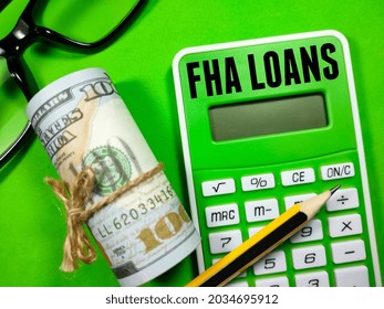 Business Concept.Text FHA LOANS Writing On Calculator With Pencil,dollar Money And Glasses On Green Background.