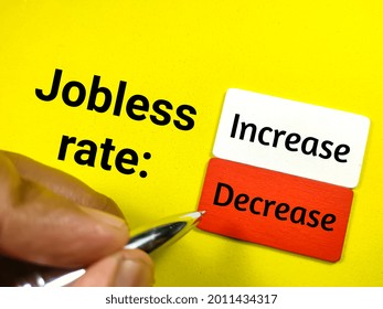 Business Concept.Text Jobless Rate: Increase And Decrease On Wooden Board With Hand Holding Pen On A Yellow Background.