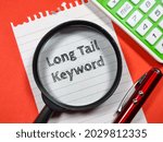 Business concept.Text Long Tail Keyword writing on notepaper with magnifying glass,calculator and pen on a red background.