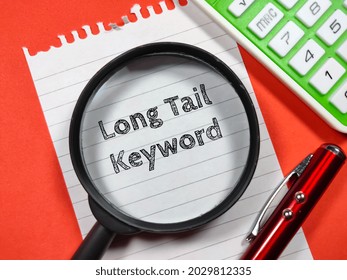 Business concept.Text Long Tail Keyword writing on notepaper with magnifying glass,calculator and pen on a red background.
