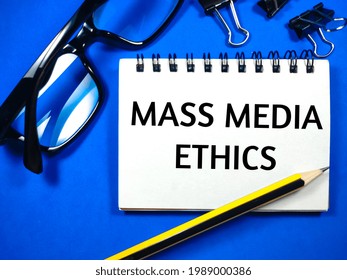 Business Concept.Text Mass Media Ethics On Notebook With Glasses,pencil And Paper Clips On Blue Background.