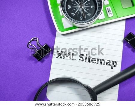 Business concept.Text XML Sitemap writing on notepaper with magnifying glass,compass,calculator and paper clips on purple background.