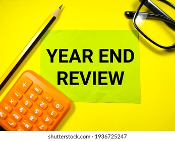 Business Concept.Text YEAR END REVIEW On Paper Note With Calculator,glasses And Pencil On Yellow Background.