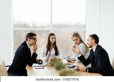 Business Conference. Business Meeting. Business People In Formal Wear Discussing Something While Sitting Together At The Table