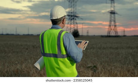 Business construction of power plants, high voltage power lines. Engineer builder, power engineer works on power lines using computer tablet. Green energy. Supply of electricity. Energy for people - Powered by Shutterstock