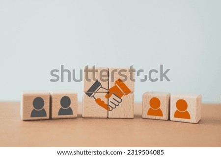 business contract. hand shaking icon on wooden cube blocks and blurred human icon for business deal and agreement concept. Teamwork process of partner and best relationship