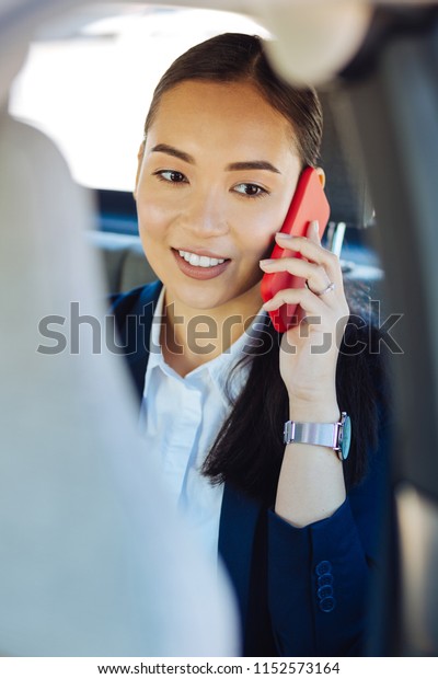 Business conversation. Joyful\
confident businesswoman holding her smartphone while making a\
call