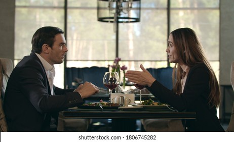 Business Couple Conflict In Restaurant. Love Couple Quarreling At Romantic Dinner In Restaurant. Aggressive Woman Screaming To Man At Restaurant Table. Angry Woman Going Out From Dinner In Cafe.