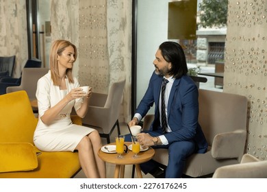 Business couple drinking coffee in hotel lobby - Powered by Shutterstock