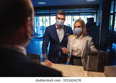 Business Couple With Face Masks Standing At Reception And Checking In The Modern Hotel. Business Trip, Relationship, Travel During Corona, COVID 19 Situation, Stay Safe, Keep Social Distance